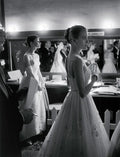 Black and white backstage scene at an awards event with women in elegant gowns preparing by a mirror