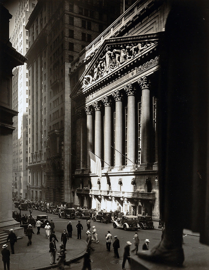 Dramatic black and white photograph of the New York Stock Exchange facade on Wall Street with 1930s cars and pedestrians.