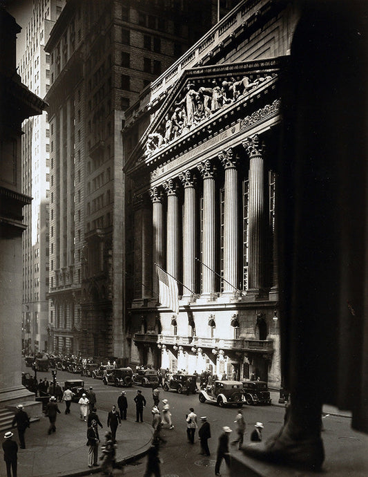 Dramatic black and white photograph of the New York Stock Exchange facade on Wall Street with 1930s cars and pedestrians.