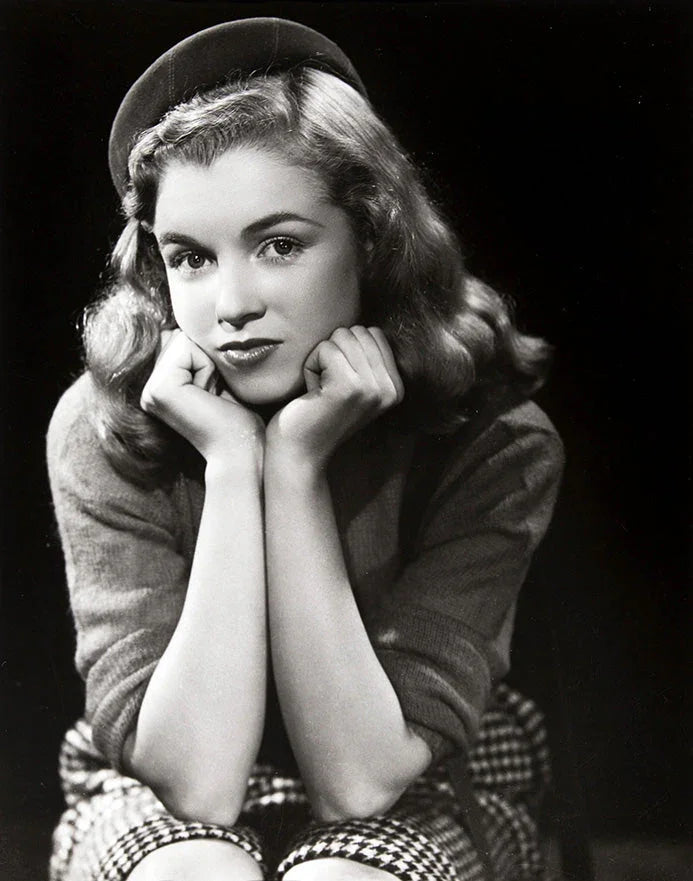 Black and white vintage portrait of a young woman with wavy hair wearing a beret and checkered skirt