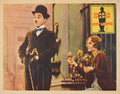 Lobby card for Charlie Chaplin's City Lights (1931) showing The Tramp looking at the blind Flower Girl who is holding a pink flower.