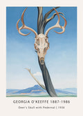Georgia O'Keeffe painting of a deer skull and antlers mounted on a dark tree trunk against a blue sky, overlooking blue mountains.