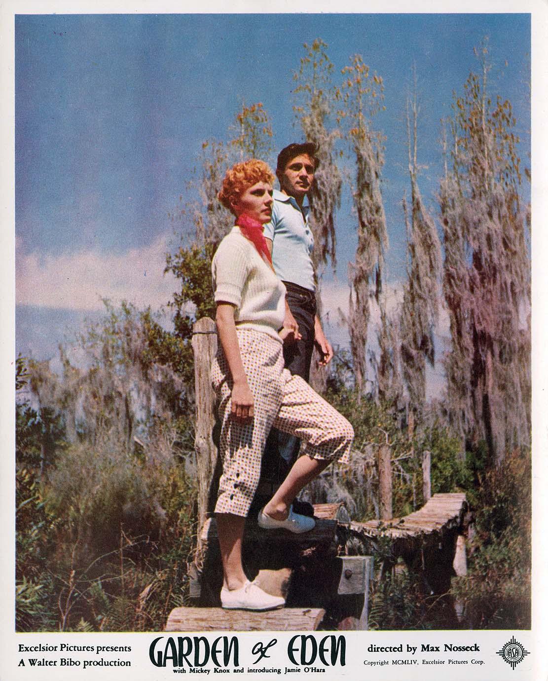 Original lobby card for the 1954 film Garden of Eden, featuring a woman with red hair and a man standing on a wooden structure in a mossy Florida swamp setting.