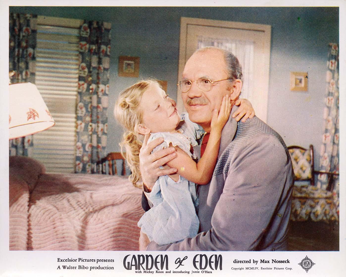 Lobby card photo print from the 1954 film Garden of Eden showing an older man embracing a small girl in a colorful, mid-century modern bedroom setting.