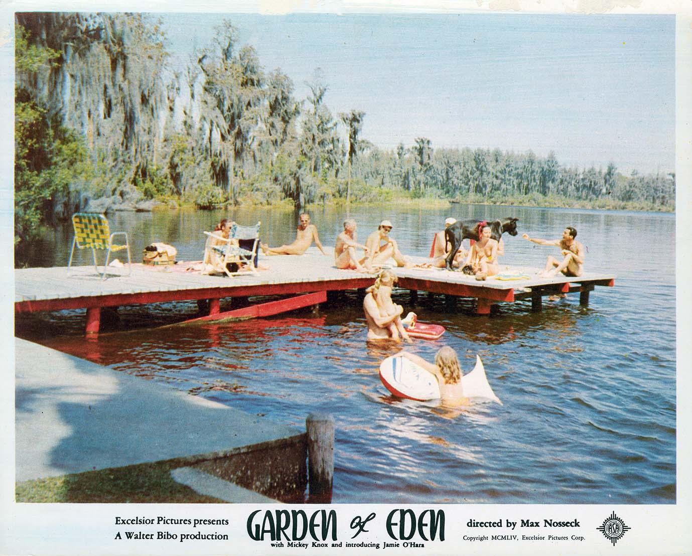 Vintage lobby card for the 1954 film Garden of Eden, showing people relaxing nude on a wooden dock by a large, moss-draped lake.