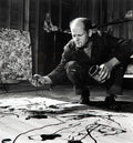 Jackson Pollock crouching and dripping paint onto a large canvas in his studio in Springs, Long Island