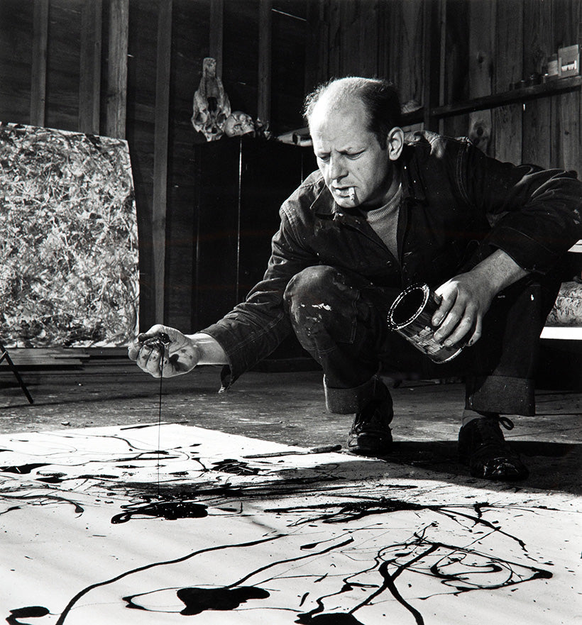 Jackson Pollock crouching and dripping paint onto a large canvas in his studio in Springs, Long Island