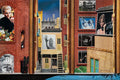 Surreal cityscape with brick buildings, framed photos of people, and a woman reaching out in a window