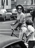Black and white photo of stylish woman with sunglasses and boy holding bicycles on city street