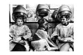 Black and white photo of two women and a dog under vintage salon hair dryers in a hair salon