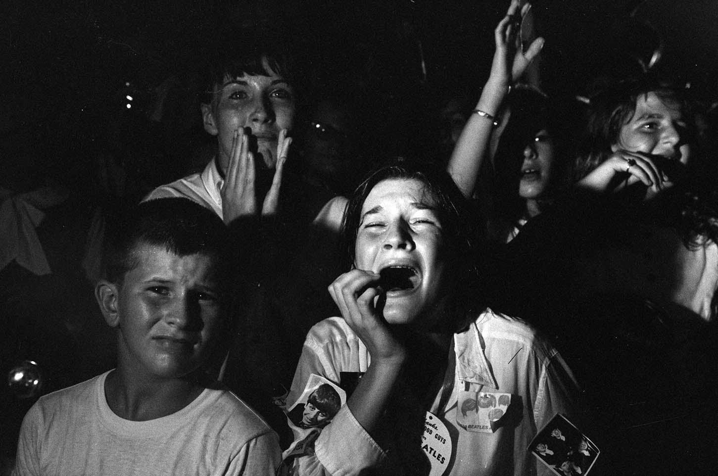 Black and white photo print showing screaming, ecstatic fans reacting intensely to The Beatles during a 1964 concert.