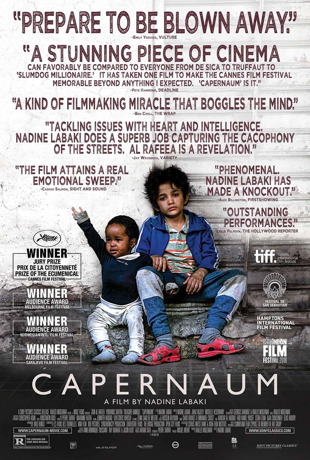 Official Capernaum movie poster showing the young protagonist, Zain Al Rafeea, and a baby sitting on concrete steps, surrounded by critical acclaim quotes.