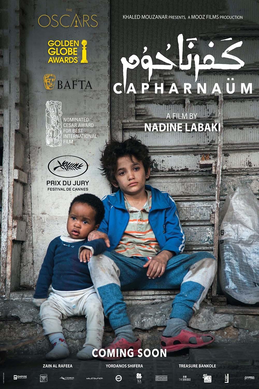 Official Capernaüm movie poster showing lead actor Zain Al Rafeea sitting beside the baby actor, against a distressed urban background, featuring major film festival laurels and awards.